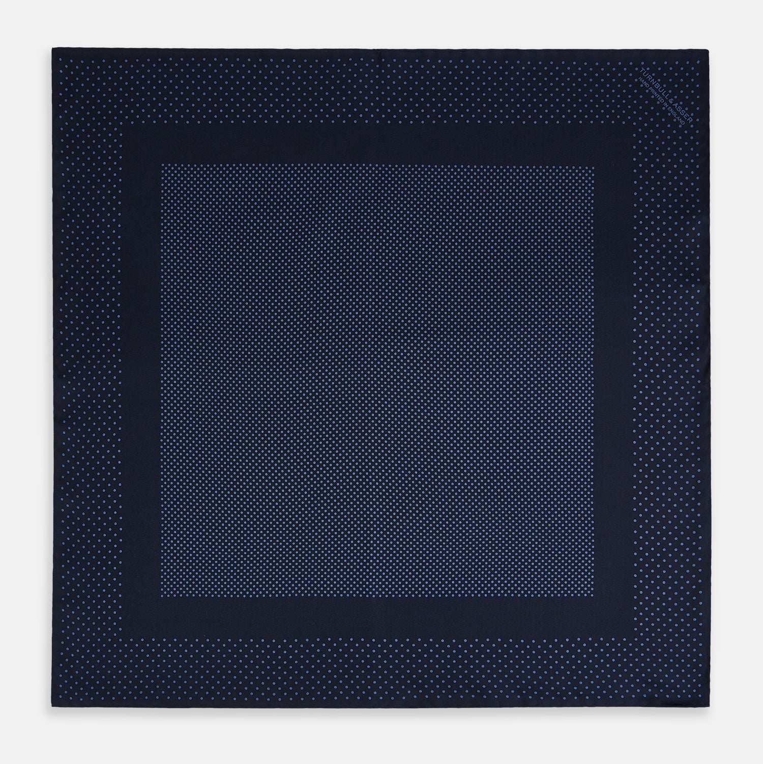 View 4 of product The Turnbull & Asser Midnight Blue Dot Silk Pocket Square features a neatly folded, handmade design with small light blue polka dots and a plain border.