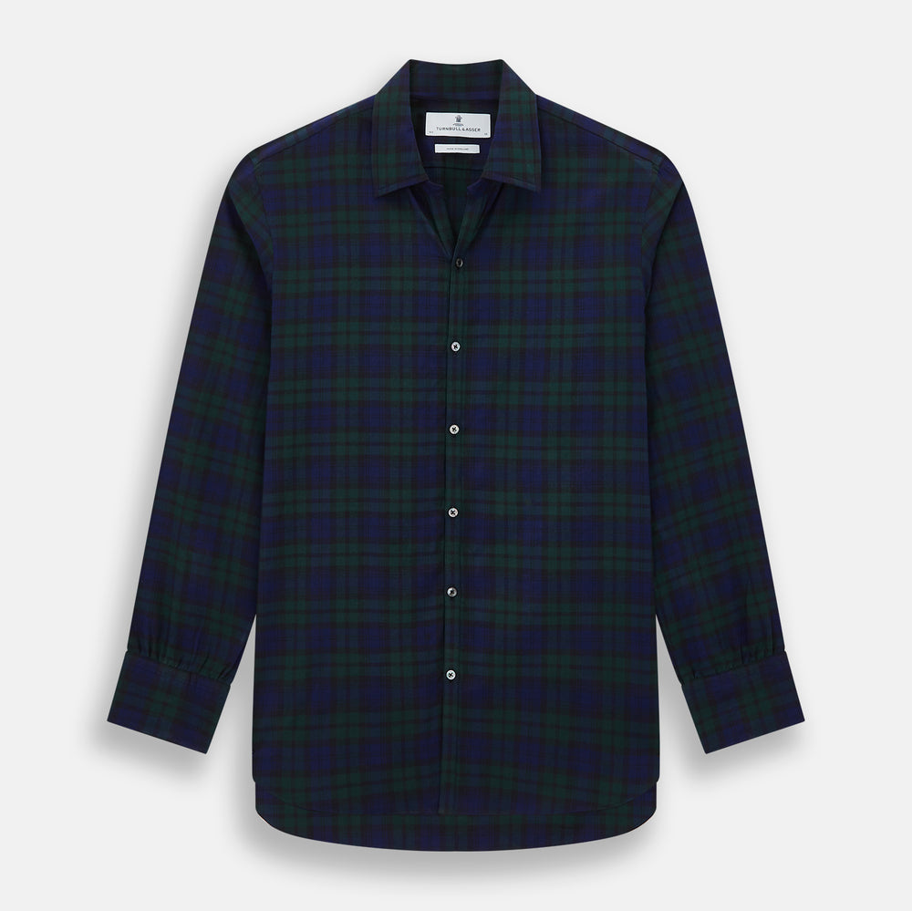 The Turnbull & Asser Black Watch Tartan Windsor Shirt is a long-sleeve, button-up shirt with a dark green and navy tartan pattern, white buttons, collar, and curved hem—showcasing British craftsmanship on a plain white background.