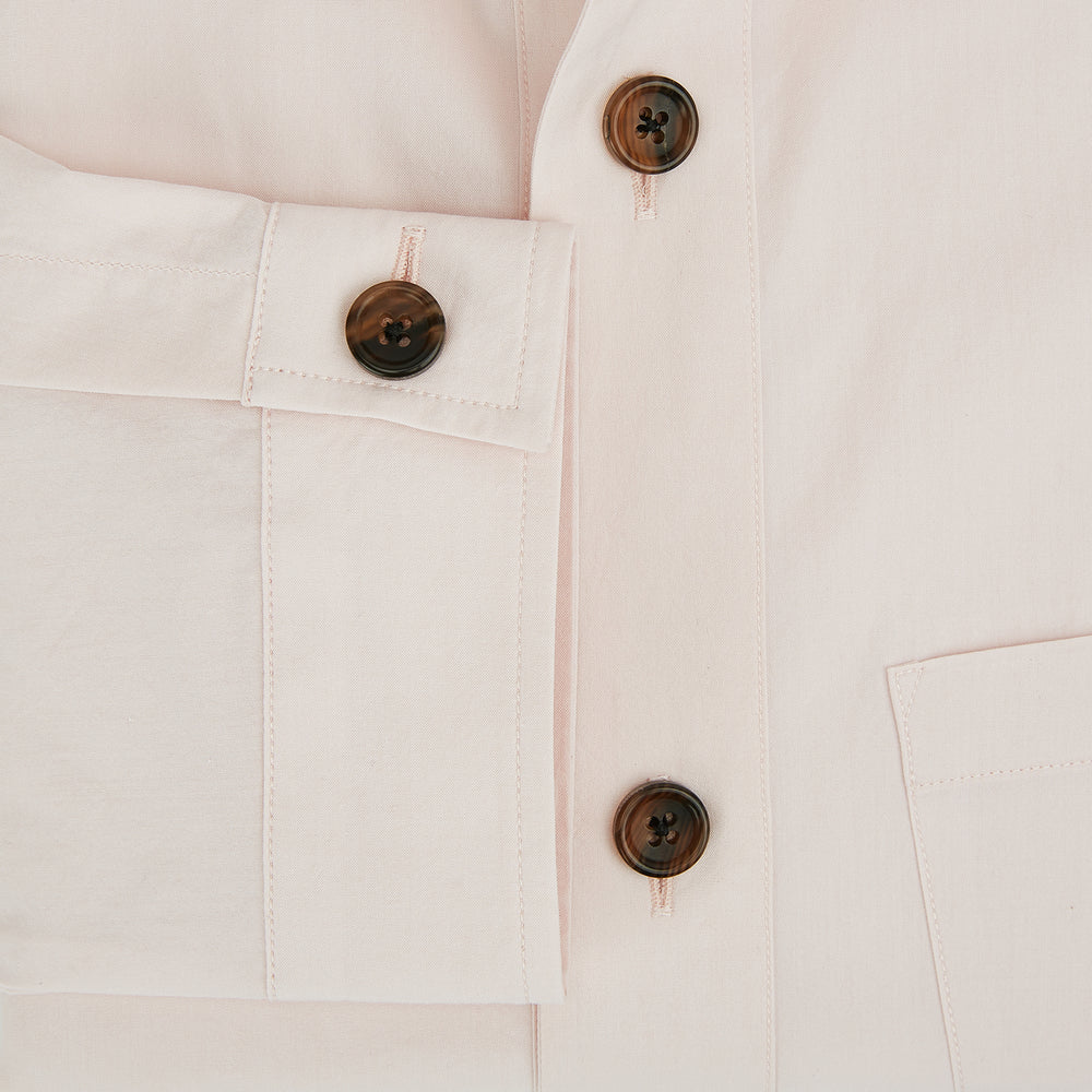 The Turnbull & Asser Pale Pink Hyde Overshirt is a long-sleeve, sanforised cotton button-up with a left chest pocket and dark buttons, shown laid flat on a white background.