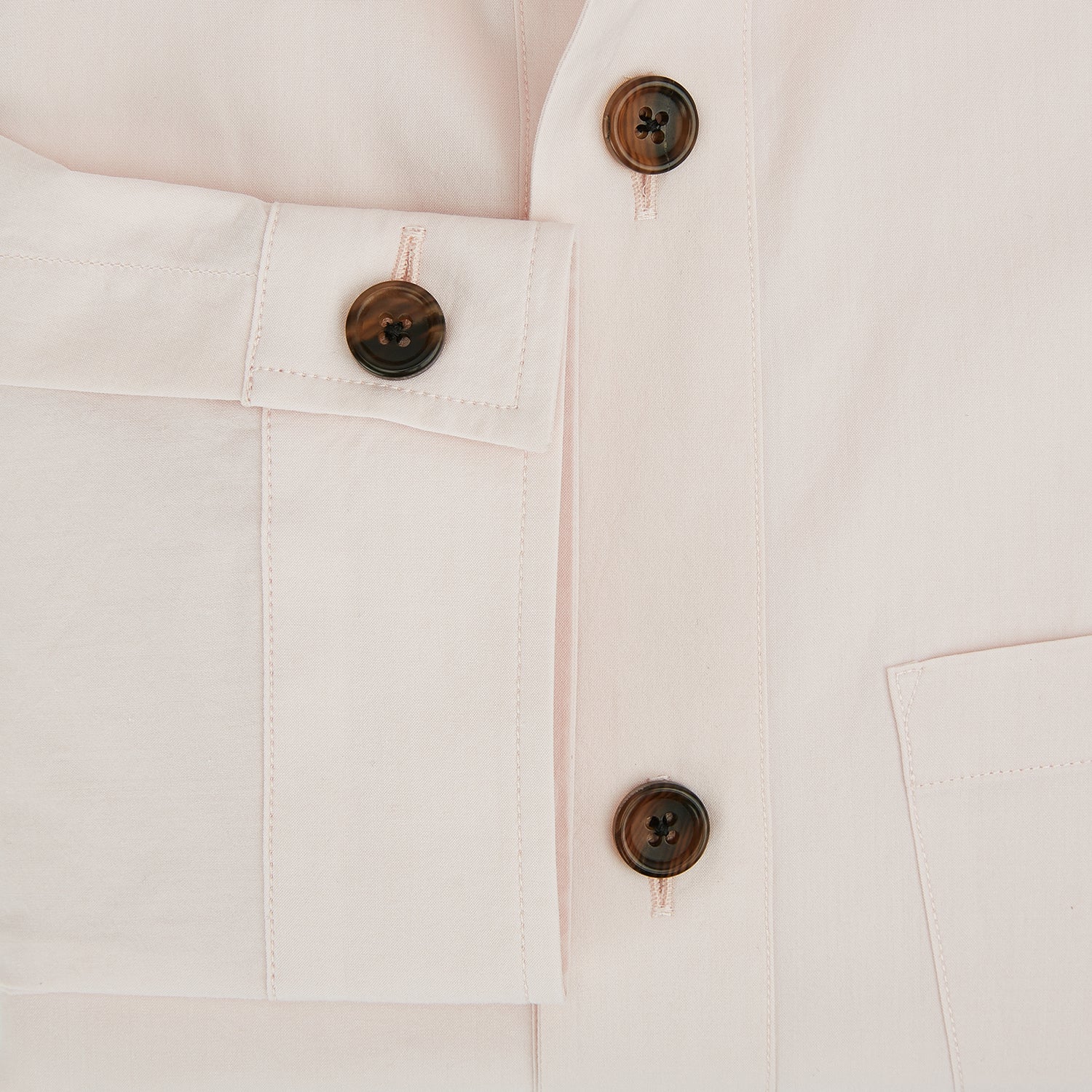View 4 of product The Turnbull & Asser Pale Pink Hyde Overshirt is a long-sleeve, sanforised cotton button-up with a left chest pocket and dark buttons, shown laid flat on a white background.