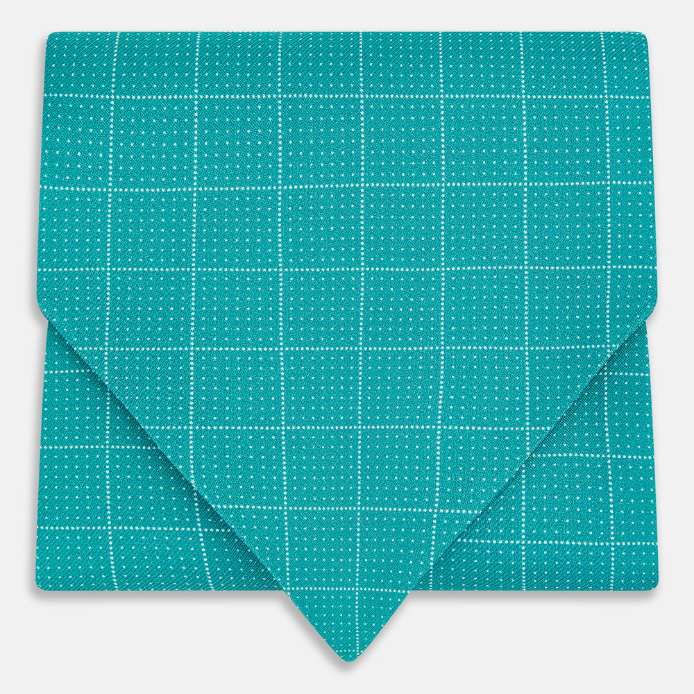 The Turquoise Dotted Check Pattern Printed Silk Cravat by Turnbull & Asser features a neatly folded diamond shape and a refined white dotted grid, showcasing classic style.