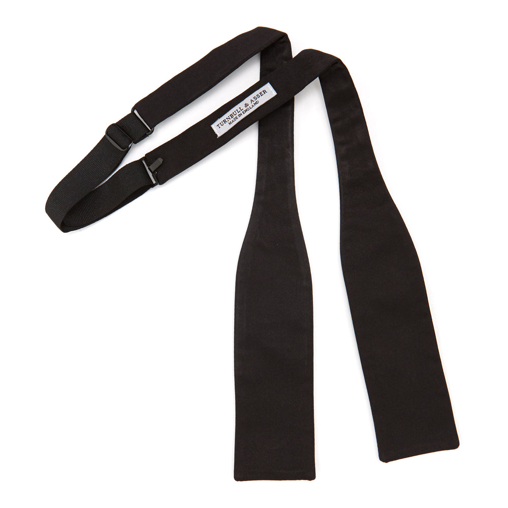The Turnbull & Asser Black Batwing Satin Bow Tie features a smooth, matte finish and is neatly tied on a plain white background—ideal for formal occasions.