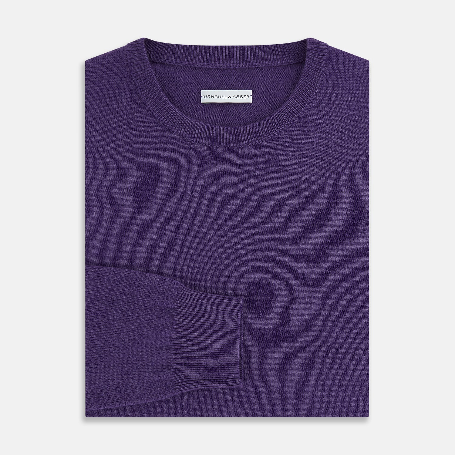 View 7 of product The Turnbull & Asser Purple Cashmere Round Neck Jumper features long sleeves, ribbed cuffs, hem, and collar for an elegant silhouette. This versatile knitwear piece is shown against a white background.