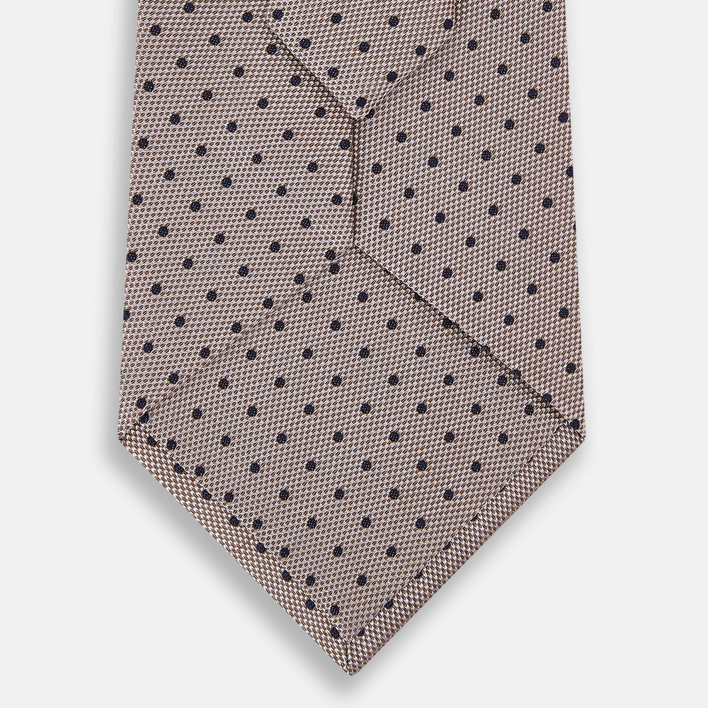 The Turnbull & Asser Navy and Lilac Micro Dot Silk Tie, featuring subtle micro dots, is the perfect refined accessory for smart outfits, shown rolled up against a plain white background.
