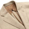View 4 of product A man wearing the Beige Wool, Silk and Cashmere Bern Jacket by Turnbull & Asser over a matching shirt and olive green pants stands against a plain light gray background, looking to his left with a neutral expression.