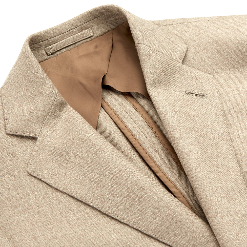 A man wearing the Beige Wool, Silk and Cashmere Bern Jacket by Turnbull & Asser over a matching shirt and olive green pants stands against a plain light gray background, looking to his left with a neutral expression.