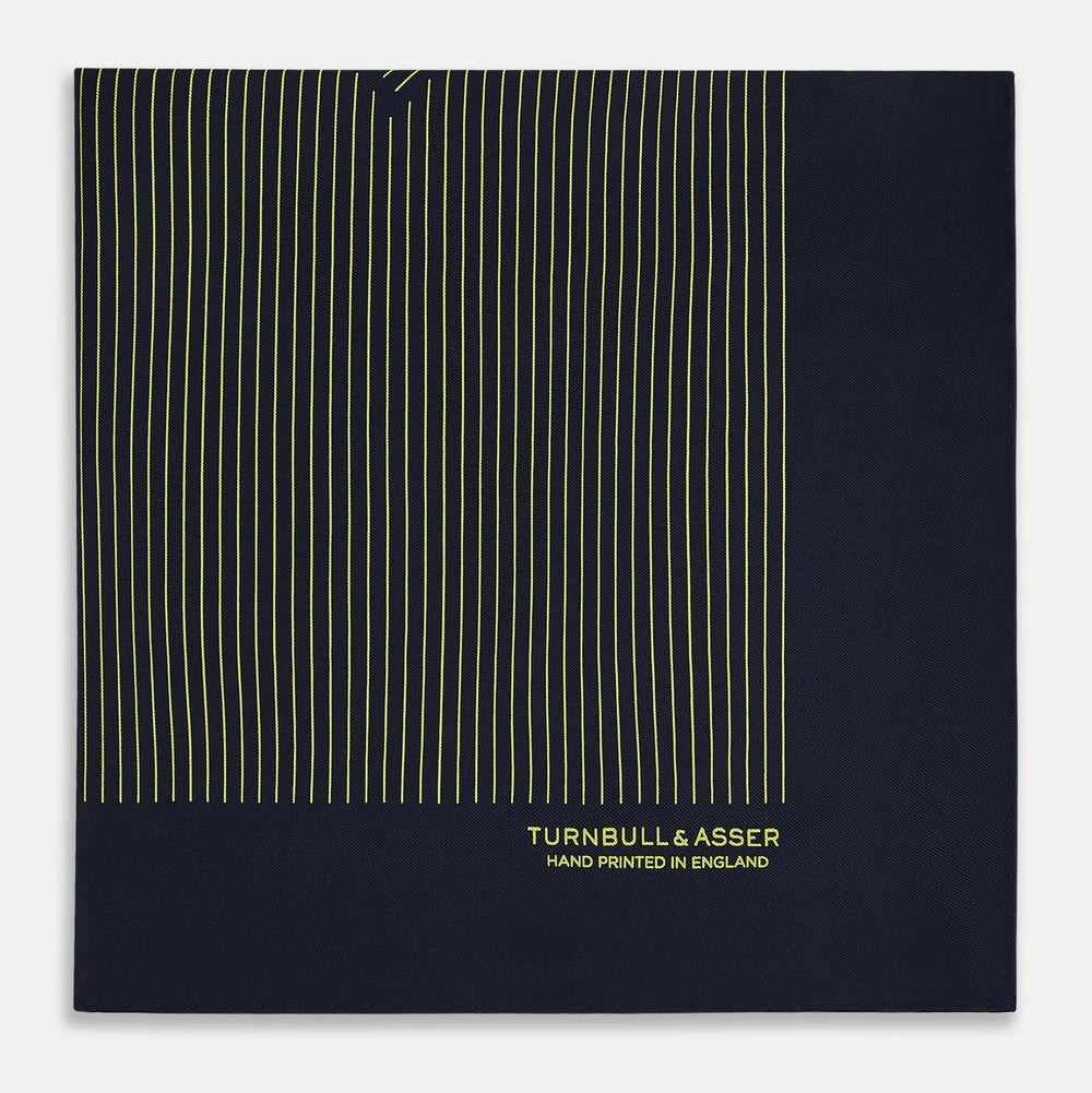 The Turnbull & Asser Navy and Gold Stripe Silk Pocket Square features light yellow vertical stripes, a folded corner, and "TURNBULL & ASSER HAND PRINTED IN ENGLAND" in gold at the bottom right.