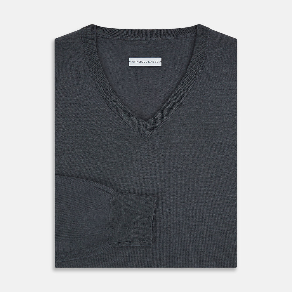 The Turnbull & Asser Charcoal Grey Merino V-Neck Jumper is shown against a white background, featuring long sleeves, a relaxed fit, and ribbed cuffs and hem for comfort.