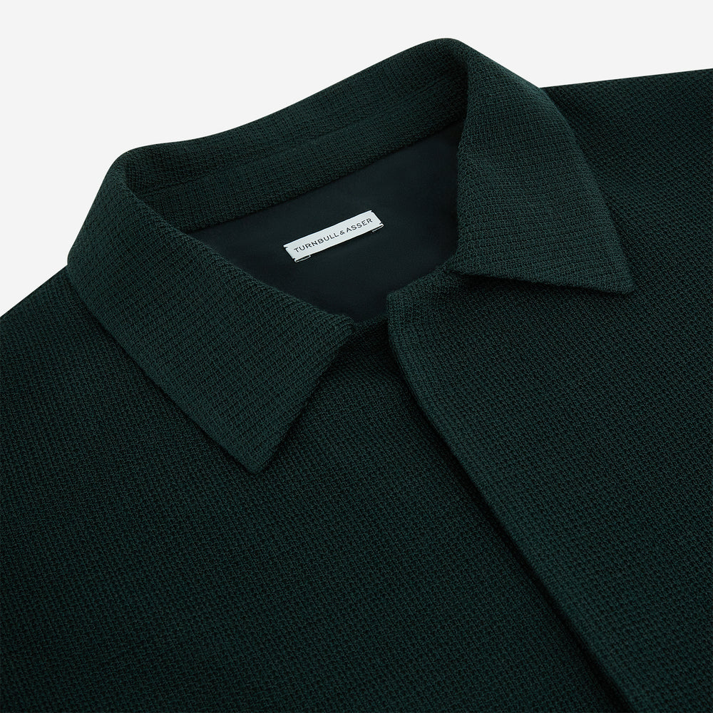 The Forest Green Greenwich Knitted Overshirt by Turnbull & Asser, crafted from Italian wool, features long sleeves, a collar, front buttons, and two chest pockets—one flap, one open—shown on a white background.