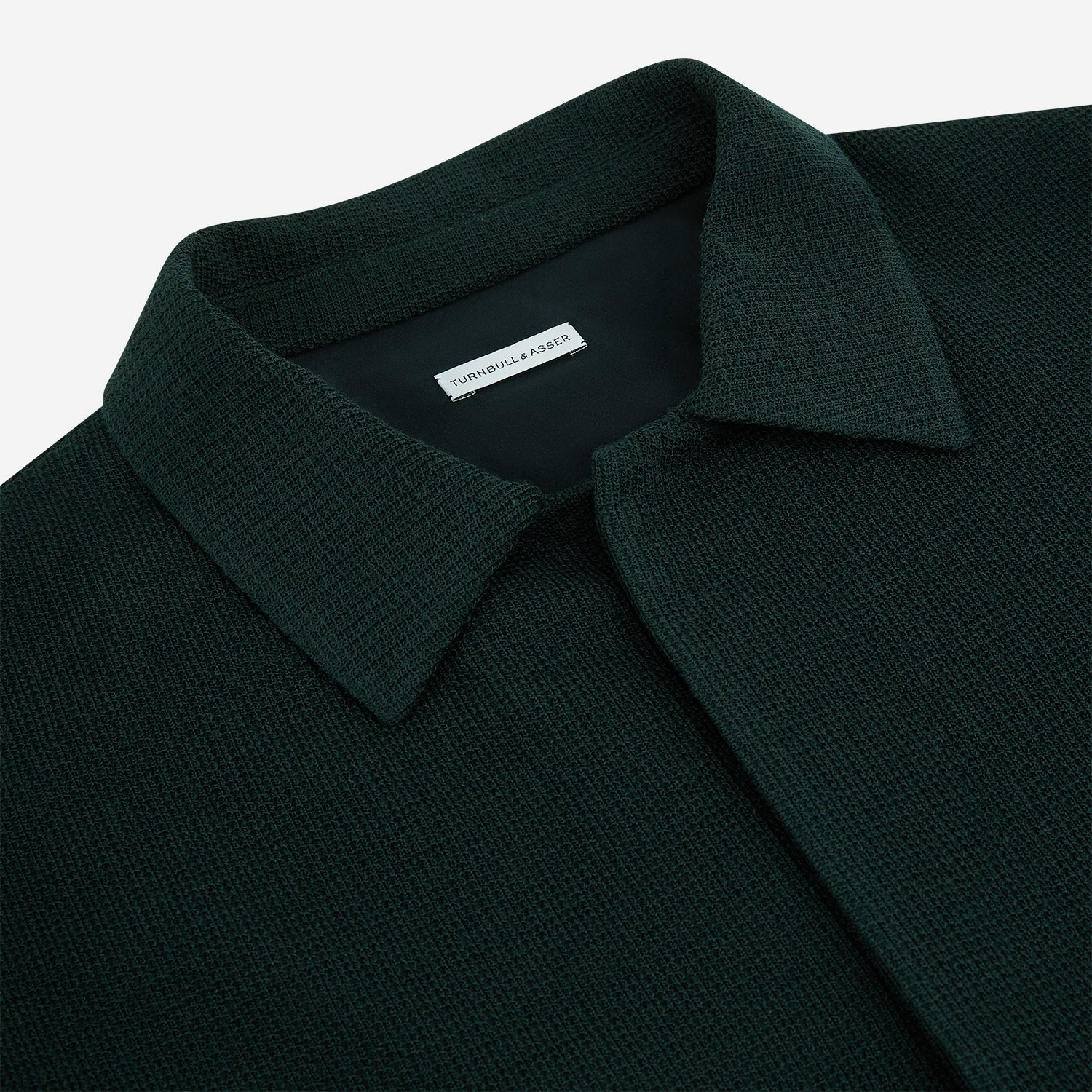 View 2 of product The Forest Green Greenwich Knitted Overshirt by Turnbull & Asser, crafted from Italian wool, features long sleeves, a collar, front buttons, and two chest pockets—one flap, one open—shown on a white background.