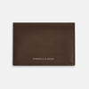 View 1 of product The Dark Brown Leather Bi-Fold Card Holder by Turnbull & Asser features neat edge stitching and the brand's name embossed in white on the front.