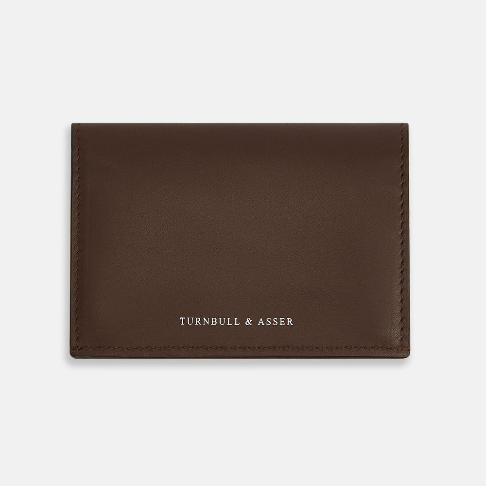The Dark Brown Leather Bi-Fold Card Holder by Turnbull & Asser features neat edge stitching and the brand's name embossed in white on the front.