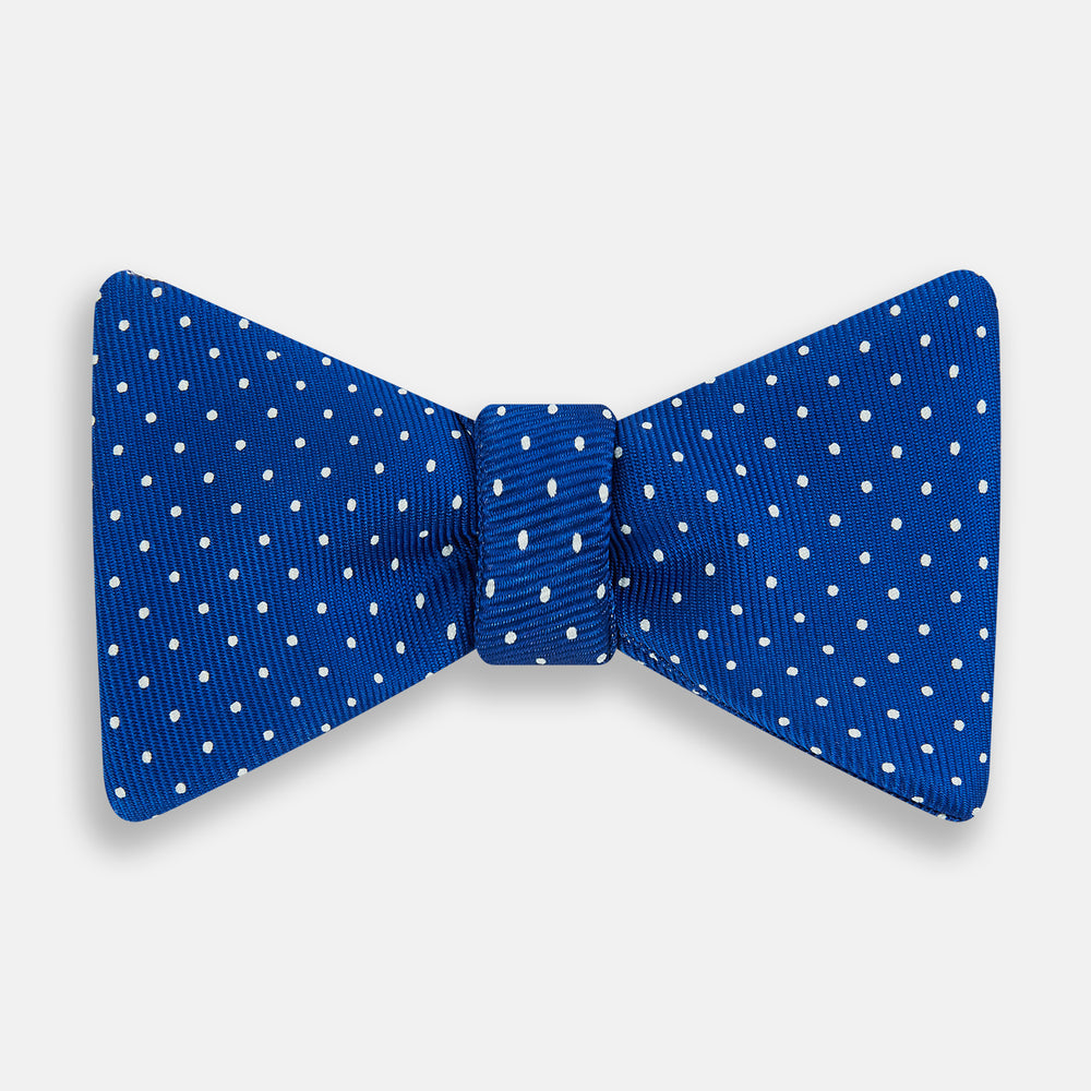 The Turnbull & Asser Electric Blue and White Spot Silk Bow Tie features evenly spaced white polka dots on vibrant silk, shown against a plain white background.