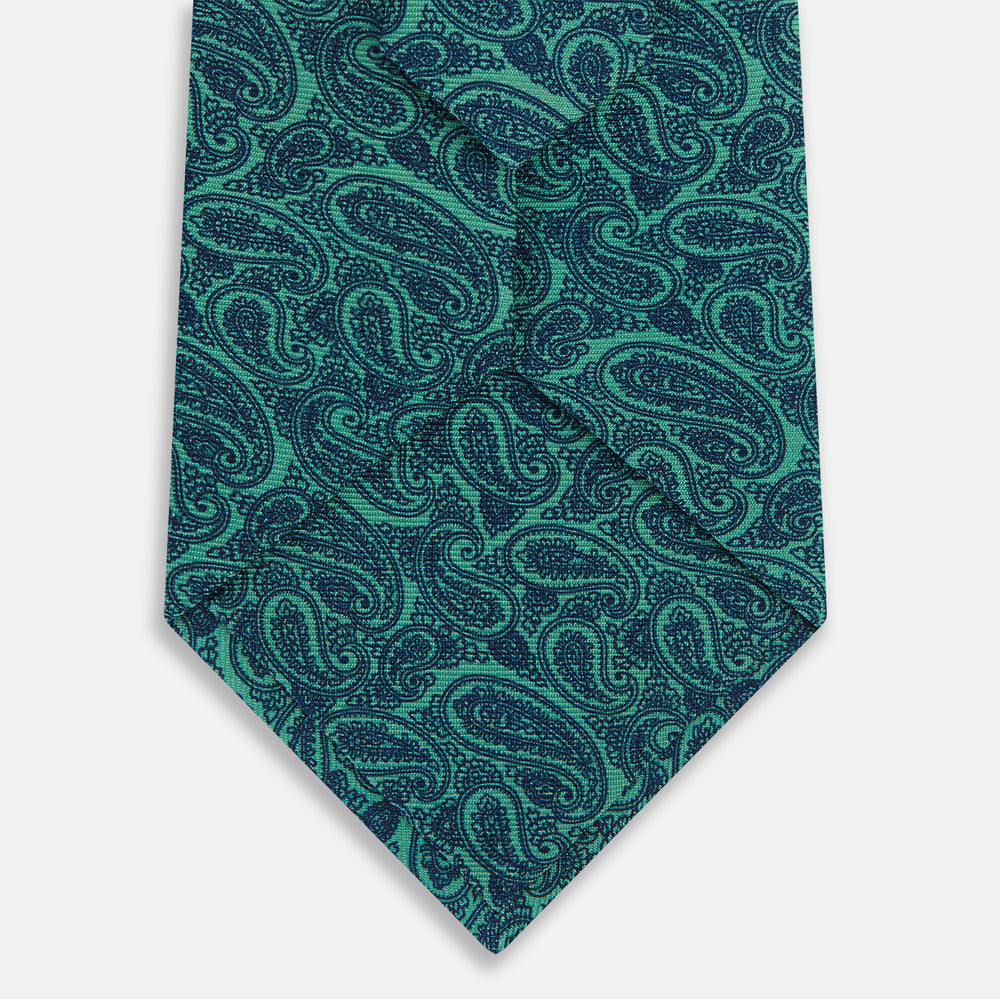 The Turnbull & Asser Kelly Green Paisley Silk Tie is shown rolled on a plain white background, featuring an intricate paisley pattern in rich green tones.