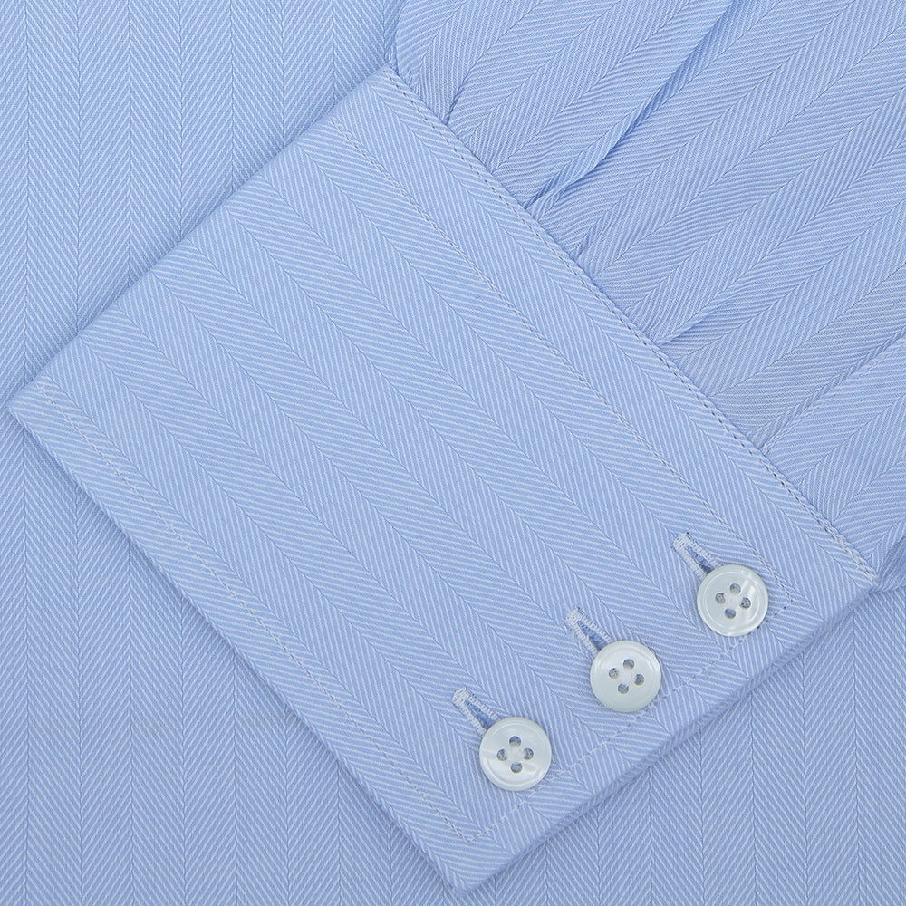 The Turnbull & Asser Light Blue Herringbone Superfine Cotton Shirt features a T&A collar and 3-button cuffs, elegantly displayed against a plain white background.