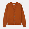 View 1 of product The Rust Lachlan Cashmere Cardigan by Turnbull & Asser features a V-neck, long sleeves, front button closure, and two front pockets—ideal for layering in smart-casual looks. Shown laid flat on a plain white background.