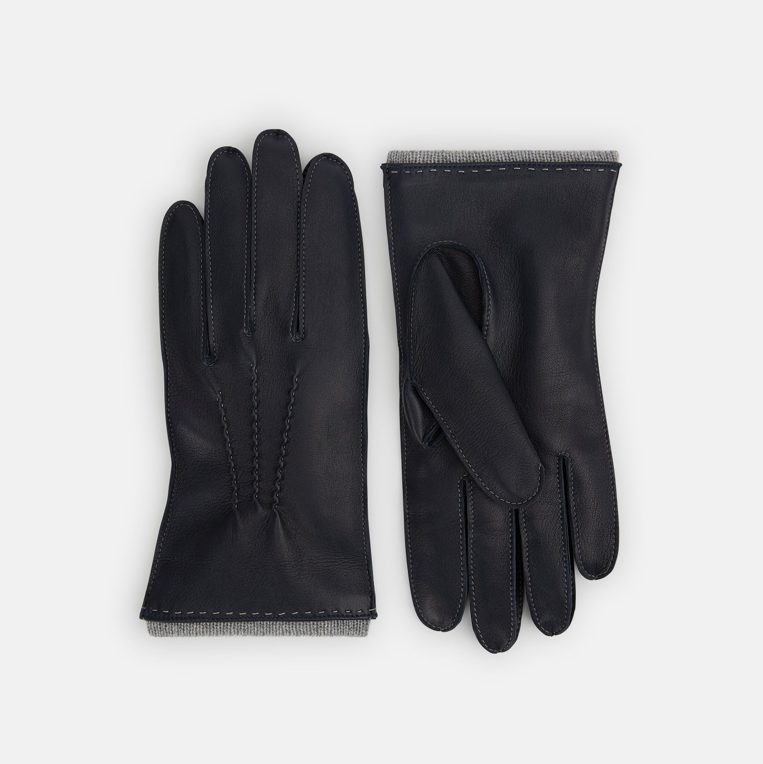 View 1 of product A pair of Turnbull & Asser Navy/Grey Cashmere-Lined Hairsheep Leather Gloves with visible stitching and soft cashmere lining. One glove is palm up, the other palm down, displayed side by side on a white background.
