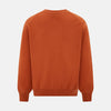 View 3 of product The Orange Cashmere Cardigan by Turnbull & Asser showcases vibrant burnt orange, a V-neck, dark buttons, ribbed cuffs and hem, long sleeves, and two front pockets. Part of the knitwear collection; displayed on a white background.