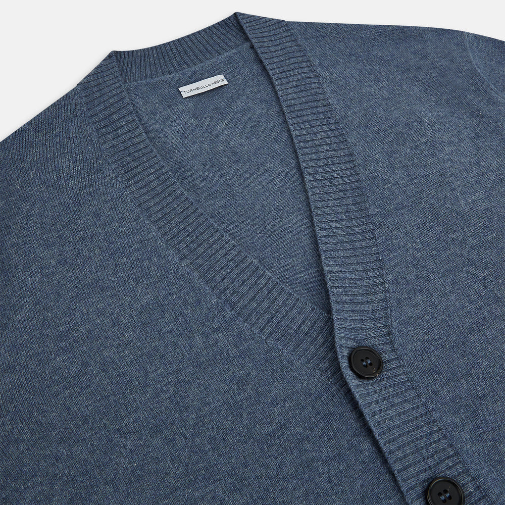 The Turnbull & Asser Blue Melange Cashmere Cardigan features a V-neck, black buttons, ribbed cuffs and hem, and two front pockets—ideal knitwear for versatile layering, shown here against a plain white background.