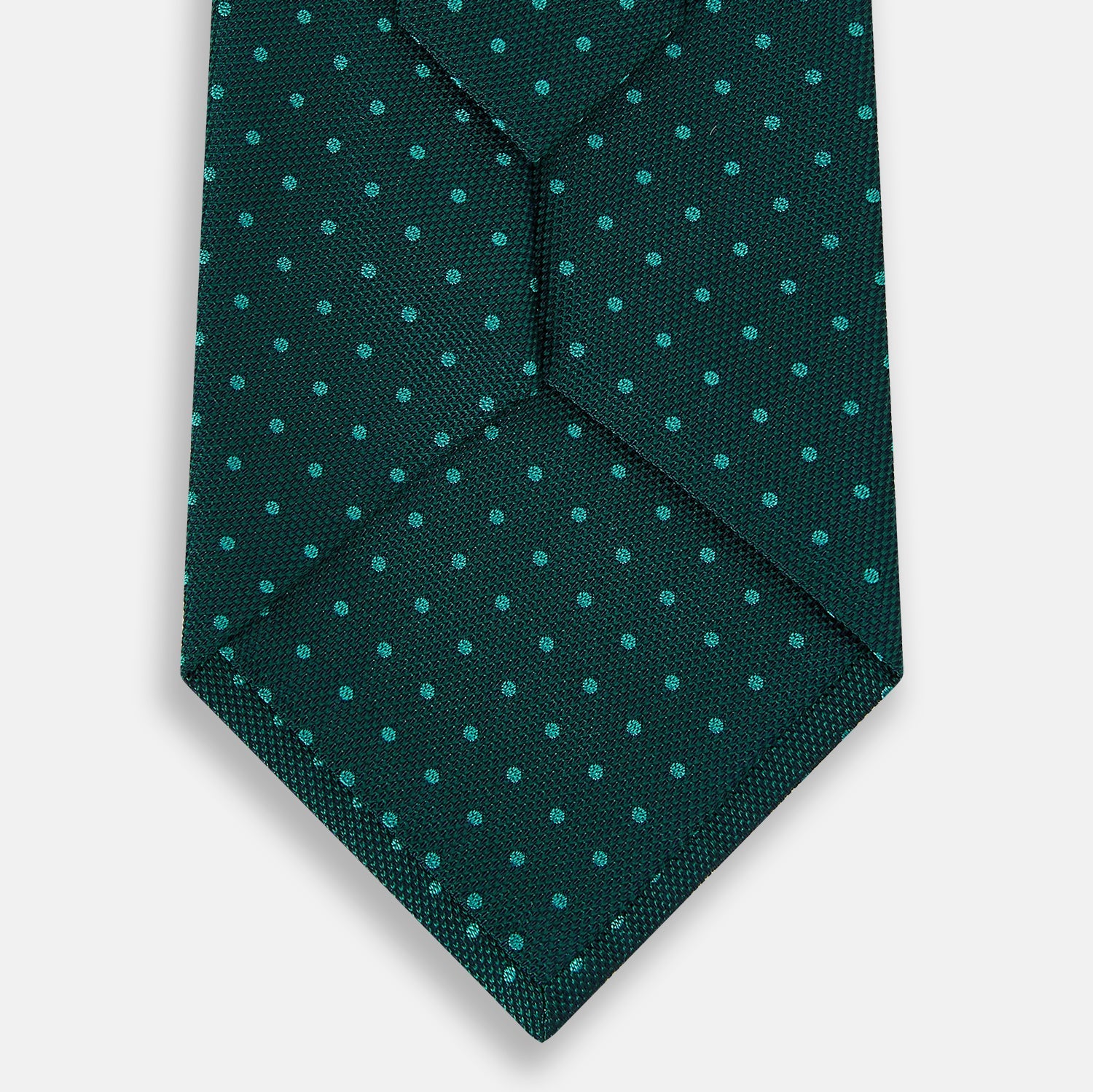View 3 of product The Turnbull & Asser Blue and Forest Green Micro Dot Silk Tie features small light blue polka dots, rolled up against a white background—an elegant men’s accessory for any occasion.