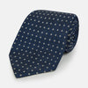 View 1 of product The Turnbull & Asser Navy and White Geometric Silk Tie, featuring a micro pattern of light blue and white squares, is displayed rolled up on a plain white background.