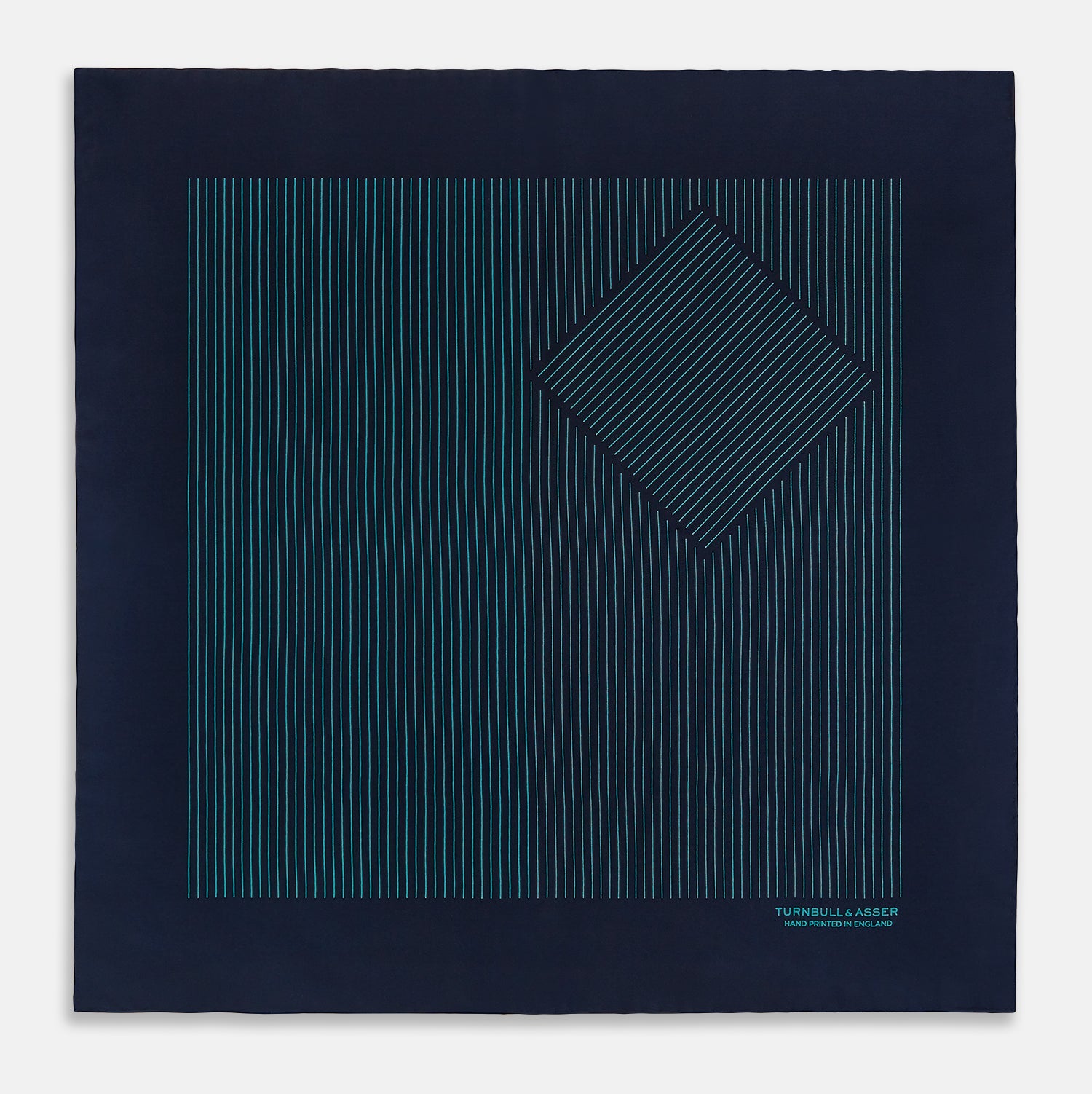 View 3 of product A Navy and Petrol Green Stripe Silk Pocket Square by Turnbull & Asser, featuring thin petrol green stripes and "Turnbull & Asser Hand Printed in England" in the bottom right corner. One corner is folded to display hand-rolled edges.