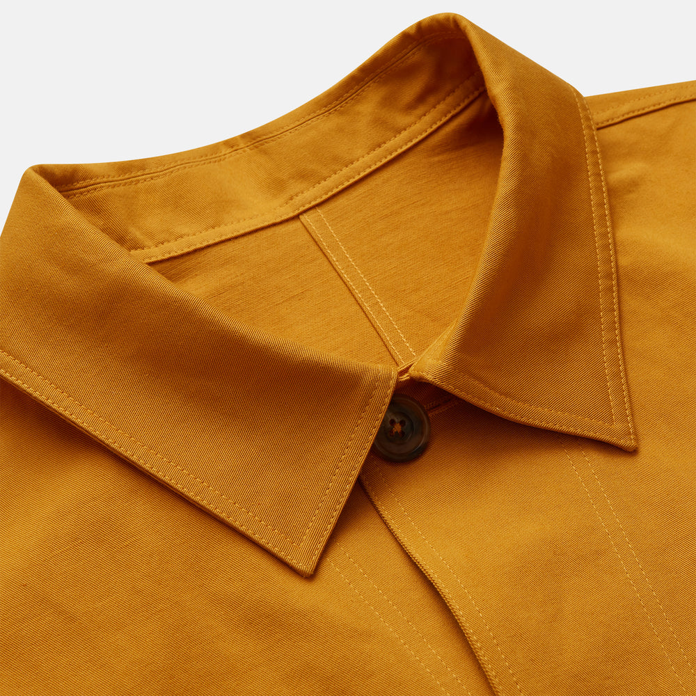 The Turnbull & Asser Ochre Cotton-Linen Remy Chore Jacket features a collar, long sleeves, brown front buttons, and three patch pockets, shown on a plain white background.