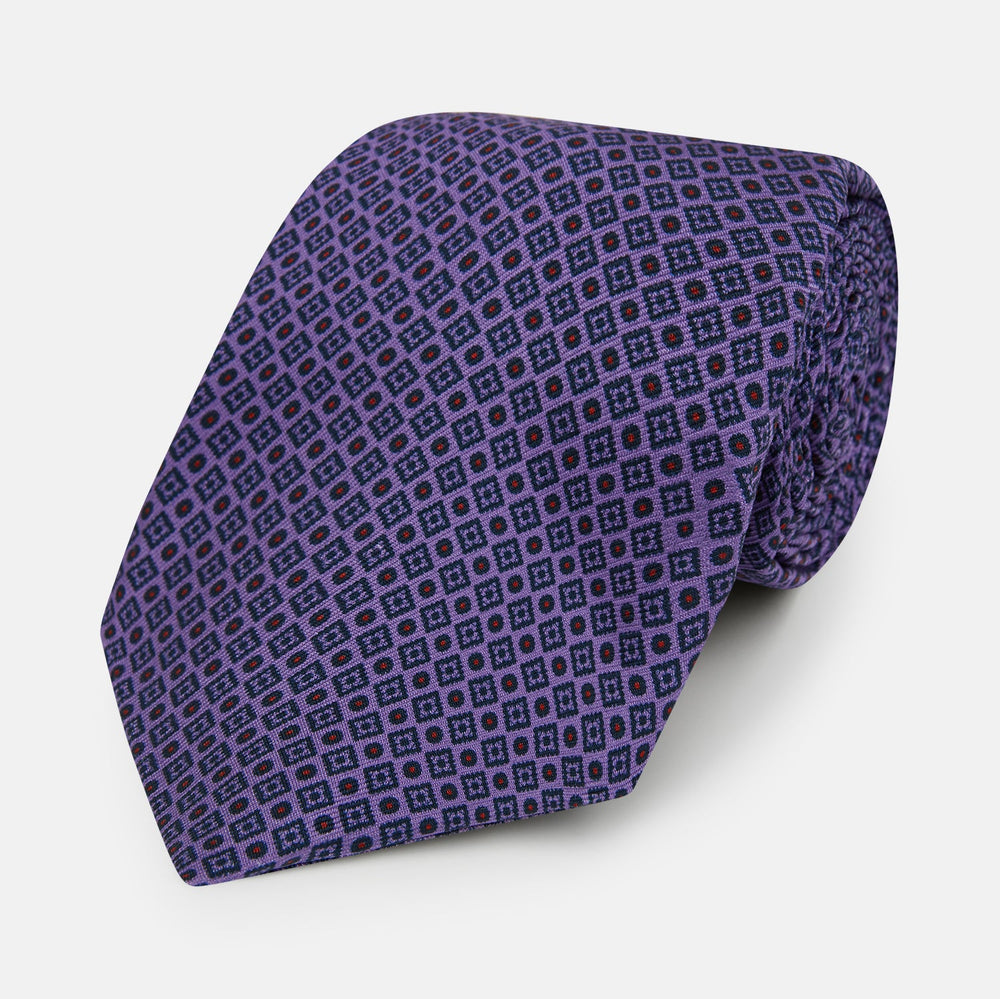 The Turnbull & Asser Purple Square and Circle Silk Tie is crafted from fine English silk, showcasing a purple design with a repeating geometric pattern of squares and circles for a refined, elegant look.