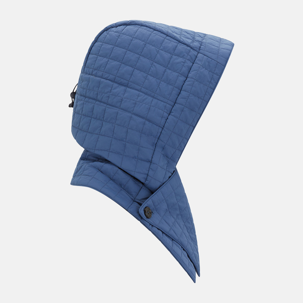 The Turnbull & Asser Azzurro Quilted Hood with Neck Warmer features a grid-stitched pattern, button closure, and overlapping front for added style. It draws inspiration from classic quilted jackets and is shown on a plain white background.