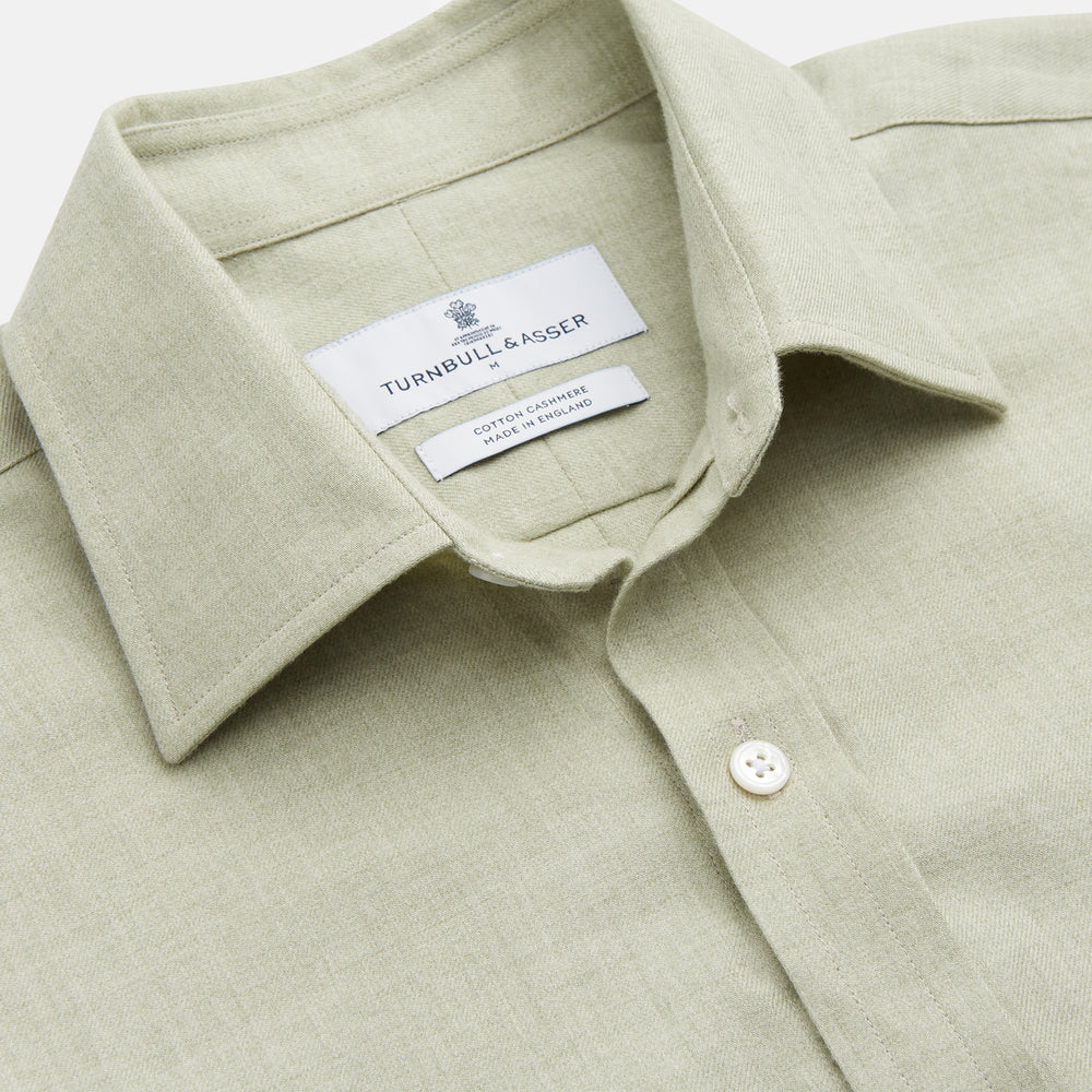 The Turnbull & Asser Soft Green Cashmerello Weekend Fit Finch Shirt features a Derby collar, long sleeves, chest pocket, white buttons, and cuffs. Laid flat on a white background.