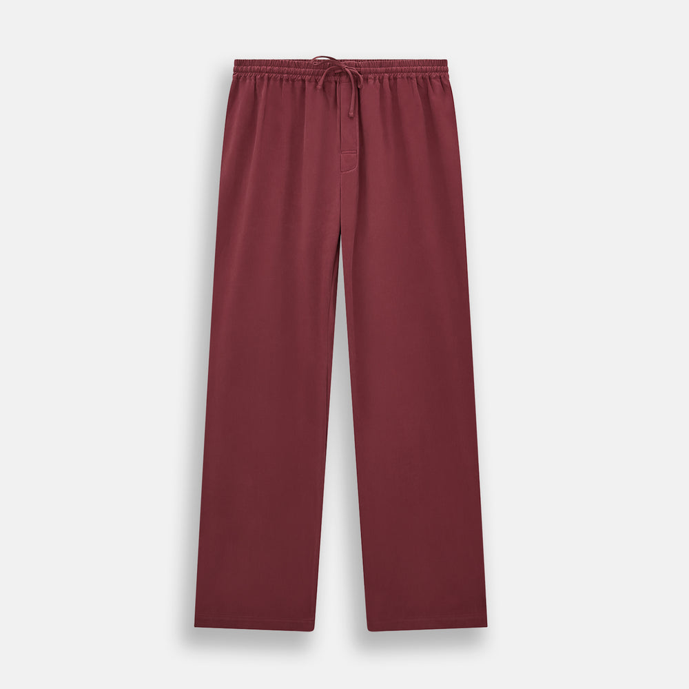 The Turnbull & Asser Burgundy Silk Pyjama Set features a long-sleeve, button-up shirt with chest pocket and matching pants with elastic waistband and side pocket, shown on a white background.