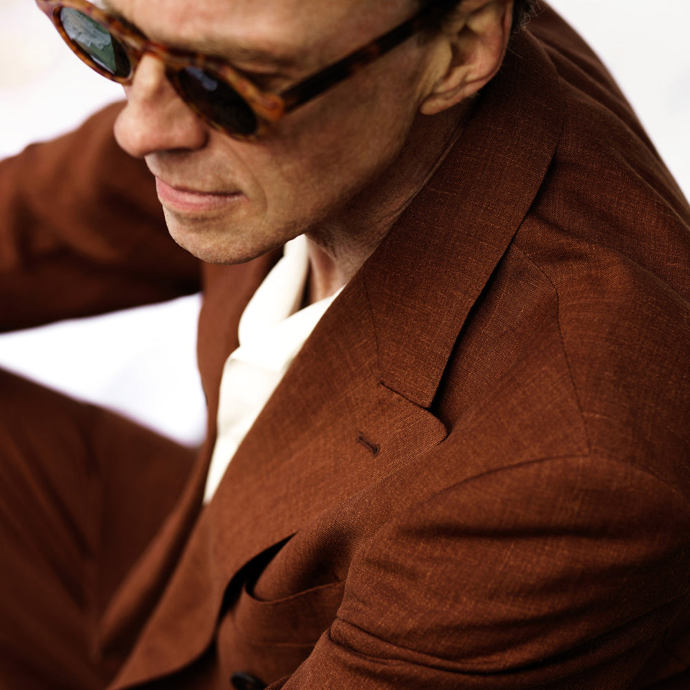 The Turnbull & Asser Rust Linen-Wool-Silk Bertie Blazer is a red double-breasted jacket with peak lapels, black buttons, and flap pockets, tailored in Italy from a luxury linen-wool-silk blend and shown on a white background.