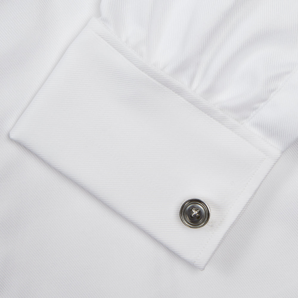 A neatly folded Turnbull & Asser White Oxford Shirt with T&A collar and double cuffs is displayed on a light blue background.