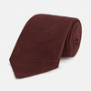 View 1 of product The Turnbull & Asser Dark Red Knitted Tie, featuring a textured finish, is shown rolled up against a white background—a stylish and versatile accessory ideal for the modern gentleman.