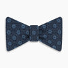 View 1 of product The Navy Medallion Silk Bow Tie by Turnbull & Asser features a navy blue base with light blue geometric grid and medallion motifs, making this sophisticated accessory stand out elegantly against a white shirt.