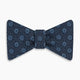 The Navy Medallion Silk Bow Tie by Turnbull & Asser features a navy blue base with light blue geometric grid and medallion motifs, making this sophisticated accessory stand out elegantly against a white shirt.