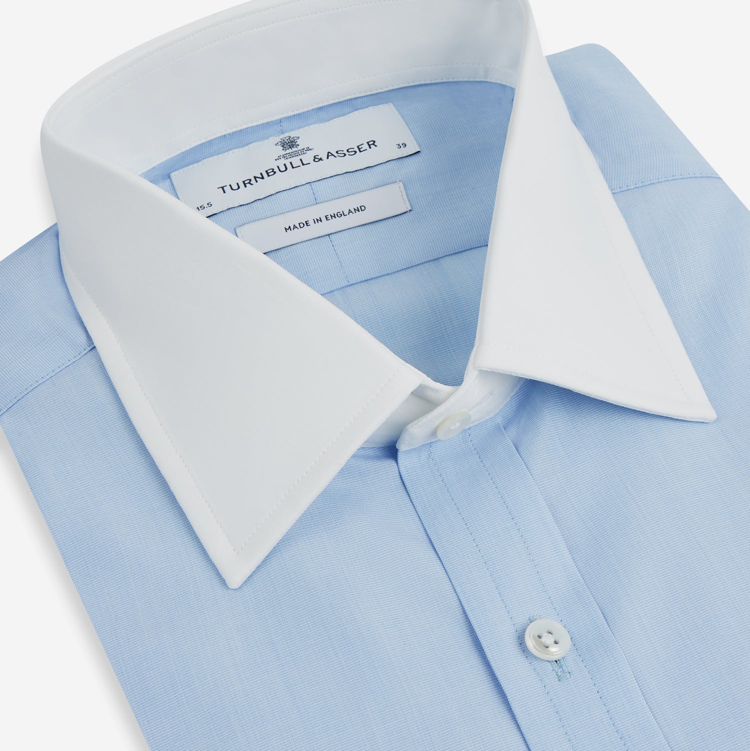 View 2 of product The Turnbull & Asser Light Blue End-on-End Shirt features a crisp white T&A contrast collar and double cuffs, shown flat on a white background.