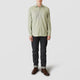 A person faces forward wearing the Turnbull & Asser Green Check Weekend Fit Shirt with Derby Collar and 1-Button Cuffs, dark cuffed jeans, and brown leather shoes against a plain light gray background.