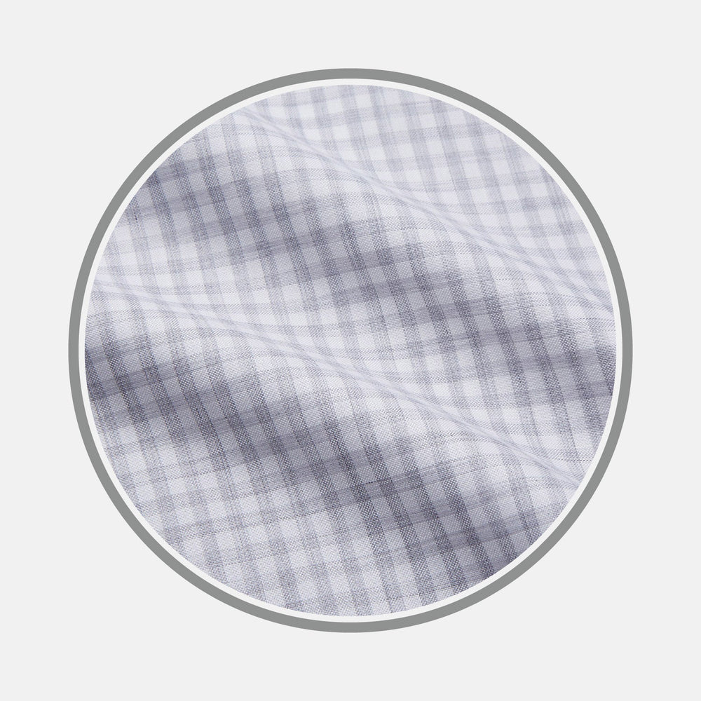 Close-up of Turnbull & Asser's NEW BESPOKE FABRIC 1318 04 in light gray and white plaid, featuring a subtle checked pattern with thin lines and a soft, slightly textured finish, shown within a circular frame.