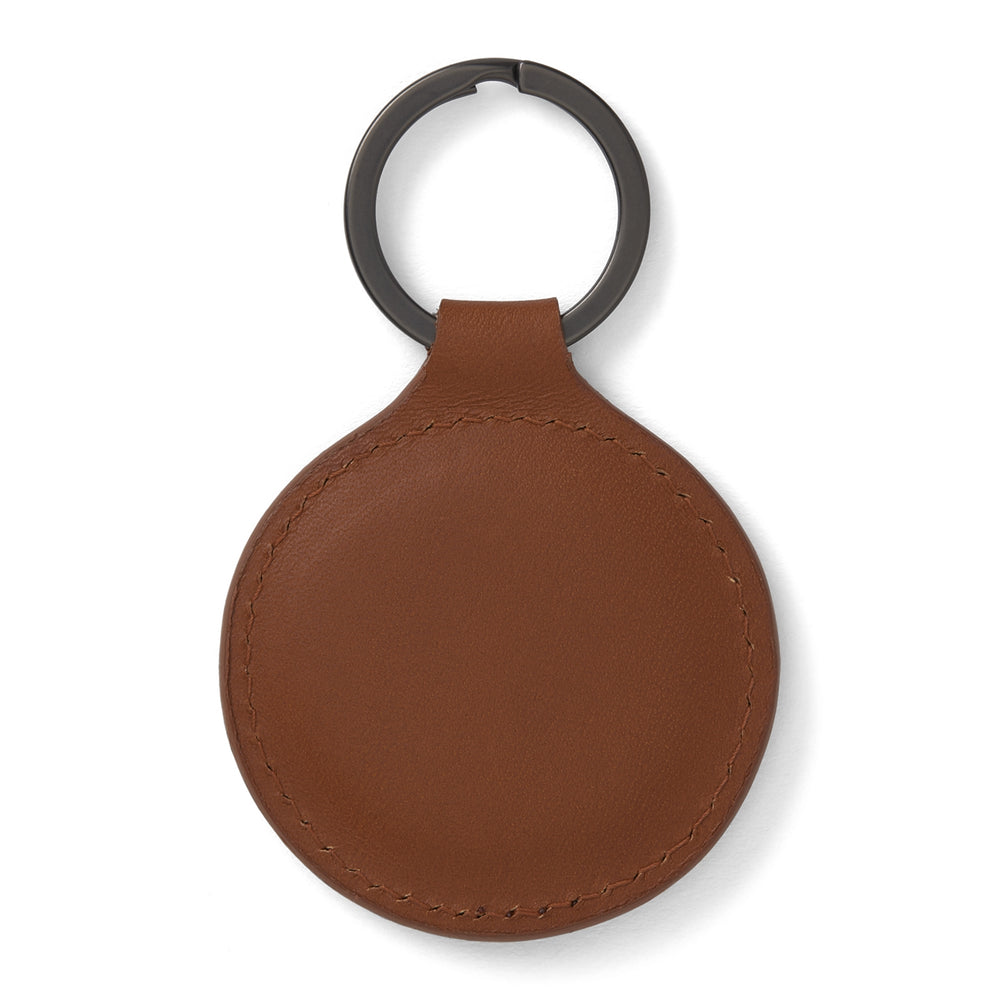 A tan circular leather fob holder by Turnbull & Asser, featuring visible stitching, embossed branding, and 'Made in England,' attached to a metal key ring.