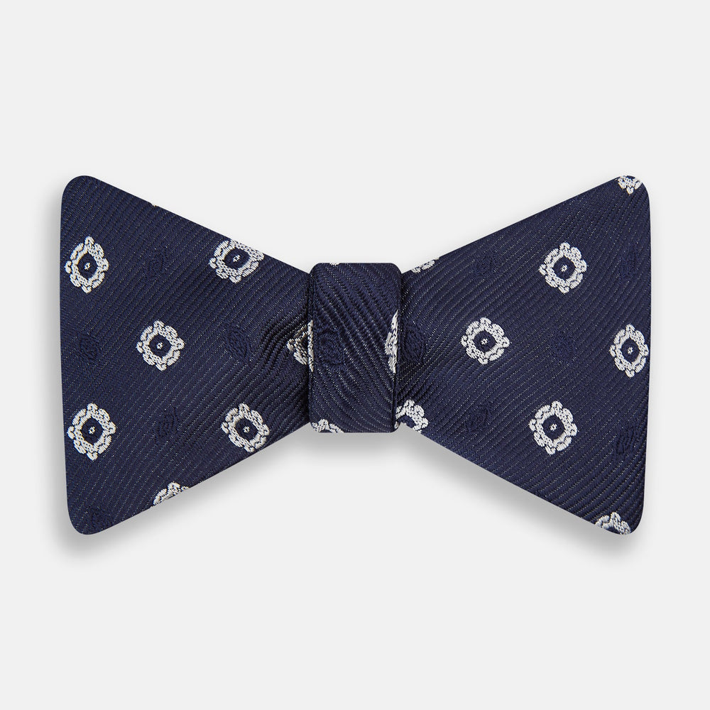 The Navy and White Motif Silk Bow Tie by Turnbull & Asser features a geometric floral pattern, adding refined elegance to formalwear. Shown on a plain white background.