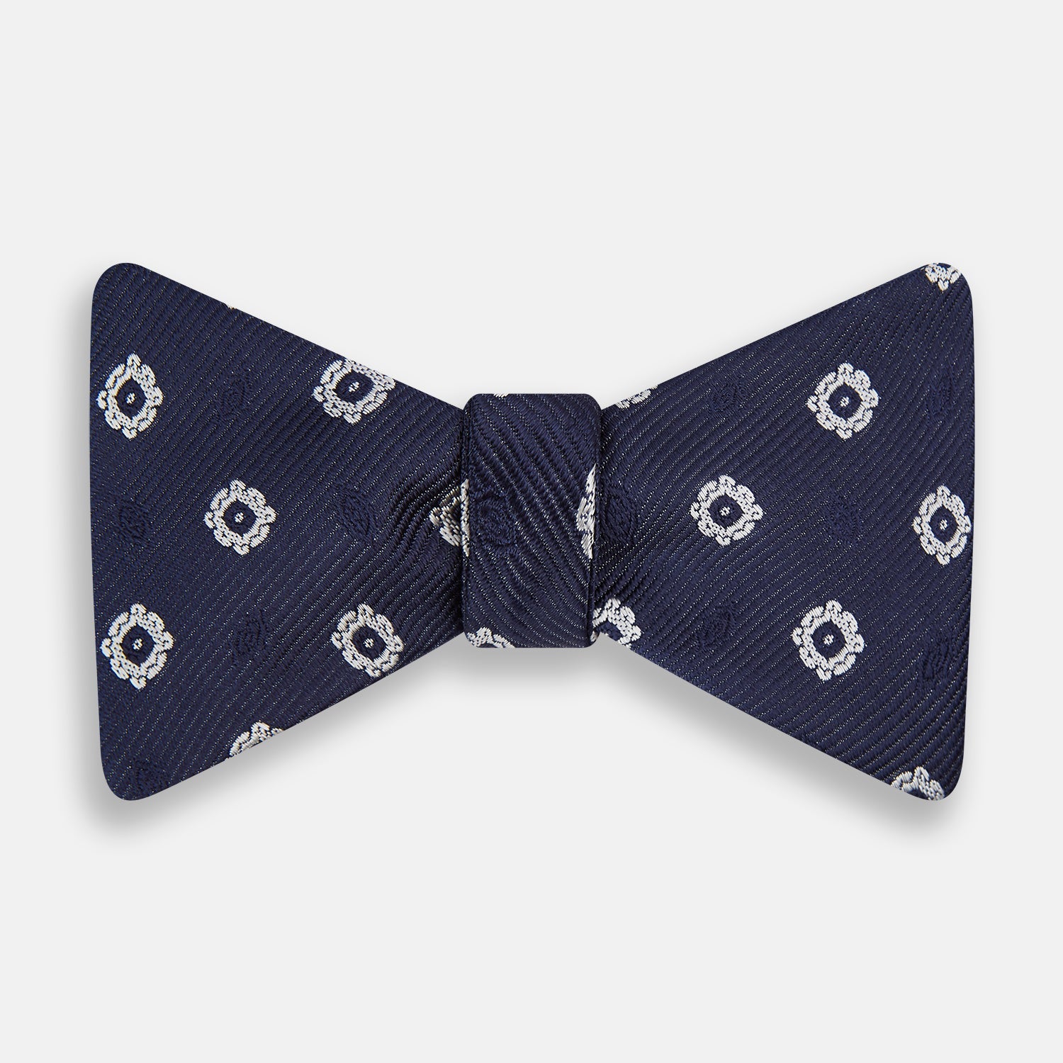 View 1 of product The Navy and White Motif Silk Bow Tie by Turnbull & Asser features a geometric floral pattern, adding refined elegance to formalwear. Shown on a plain white background.