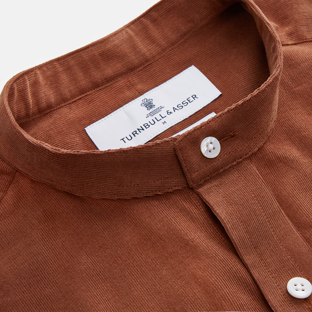 The Turnbull & Asser Rust Cotton Weekend Fit Blake Shirt features long sleeves, a stand collar, and white buttons—an ideal casual piece displayed flat on a white background.