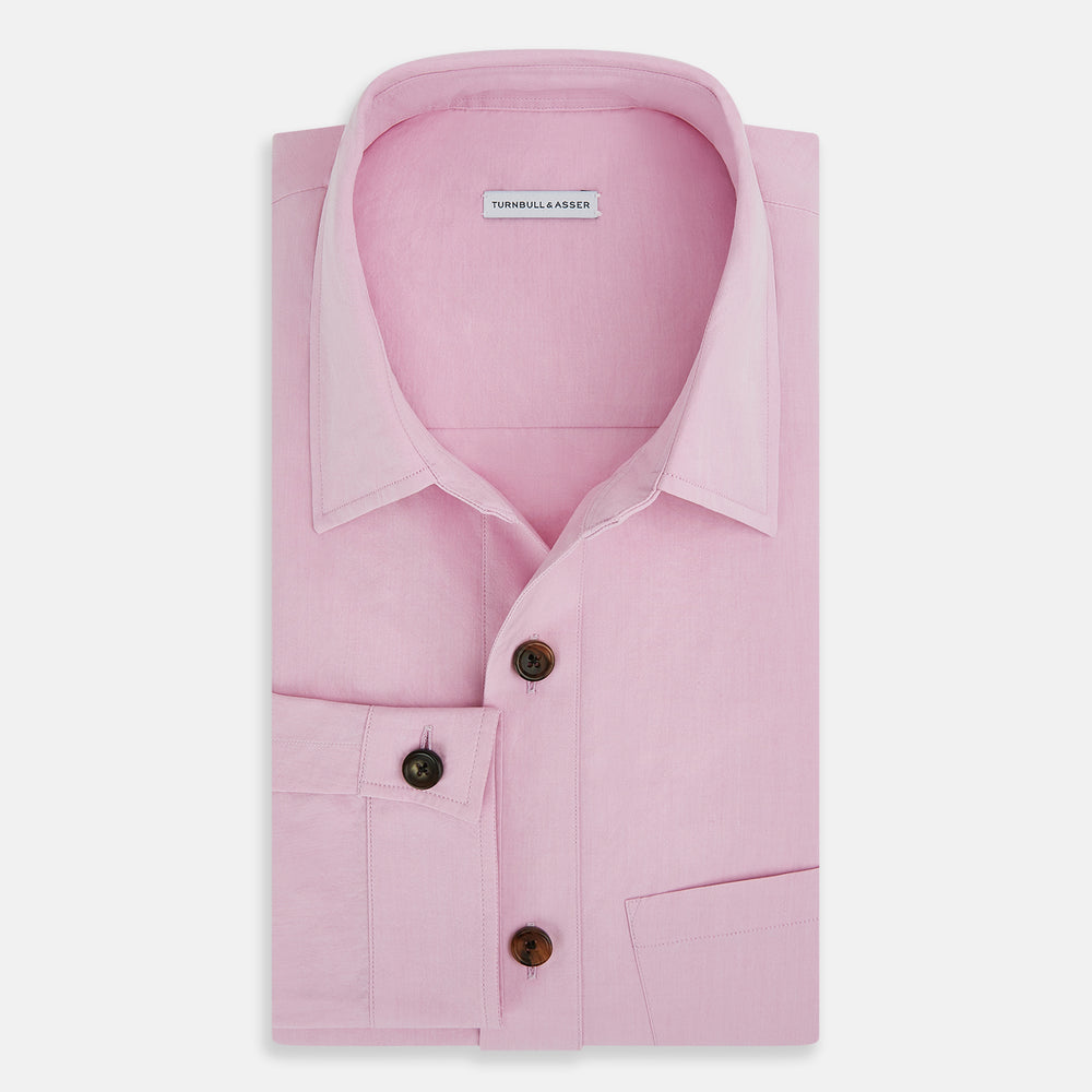 The Pink Hyde Overshirt by Turnbull & Asser is a long-sleeved, light pink sanforised cotton shirt with a left chest pocket and dark buttons—an elegant, laid-back alternative to a blazer.