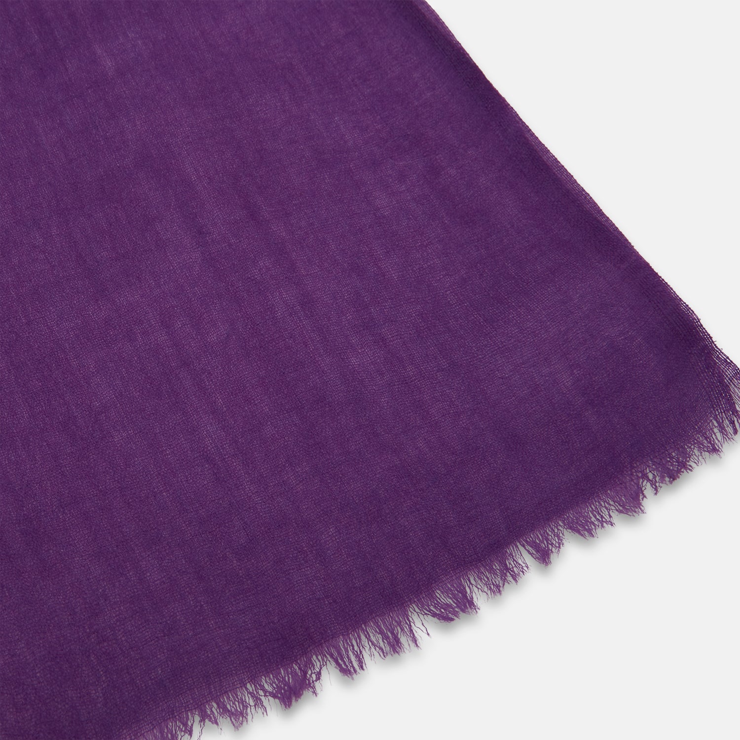 View 2 of product The Purple Cashmere Scarf by Turnbull & Asser is a luxurious, lightweight accessory, hand-dyed in purple with subtle frayed edges and a loose central knot, elegantly displayed on a plain white background.