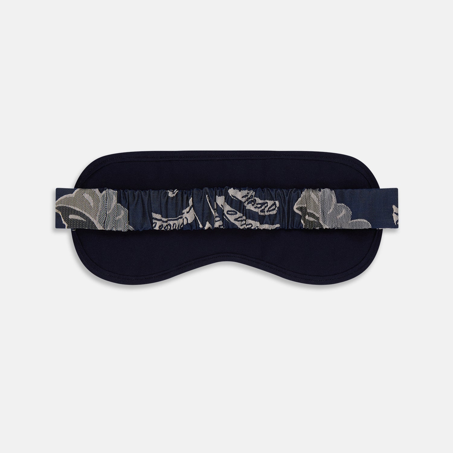 View 4 of product The Turnbull & Asser Navy Bloomsbury Jacquard Cashmere Lined Sleep Mask and Bag features a dark blue backdrop with beige, olive green, and gray floral patterns, plus elastic straps for comfort.