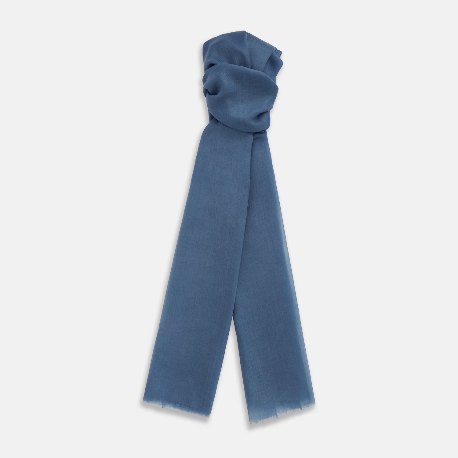 View 1 of product The Turnbull & Asser Mid Blue Cashmere Scarf is lightweight and slightly sheer, hand-dyed with frayed ends, shown loosely knotted against a white background.
