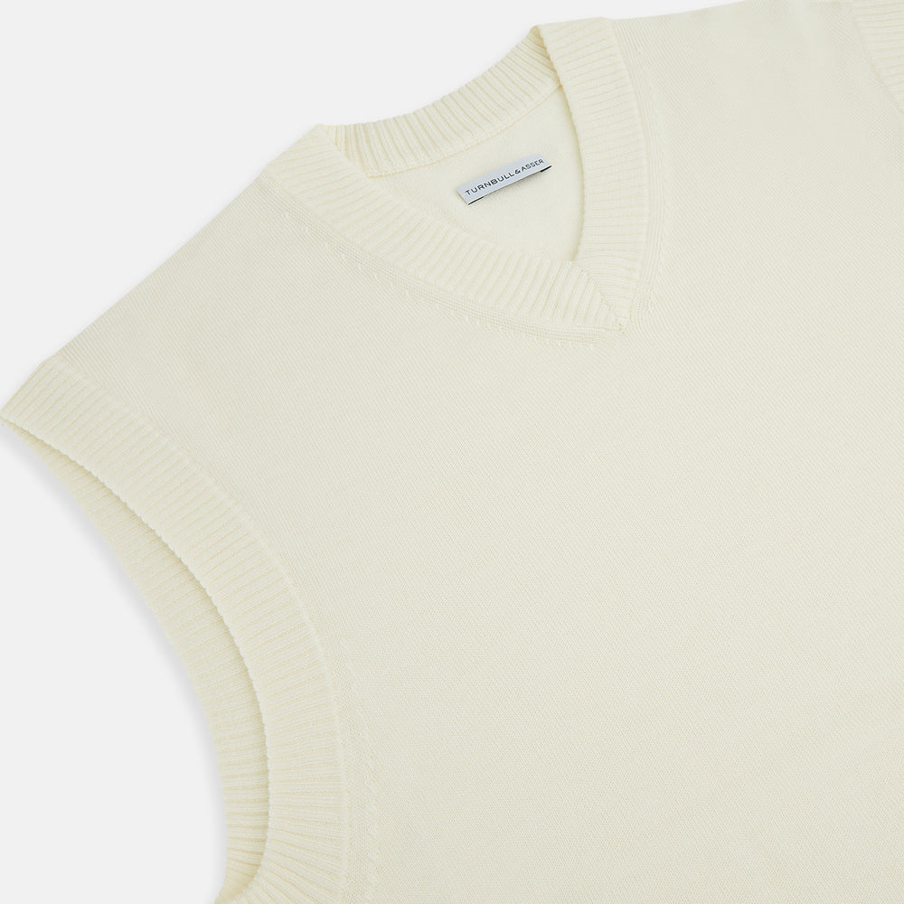 The Ecru Fine Merino V-Neck Vest by Turnbull & Asser is a sleeveless gentleman’s sweater with ribbed edges in cream knit, shown against a plain white background.