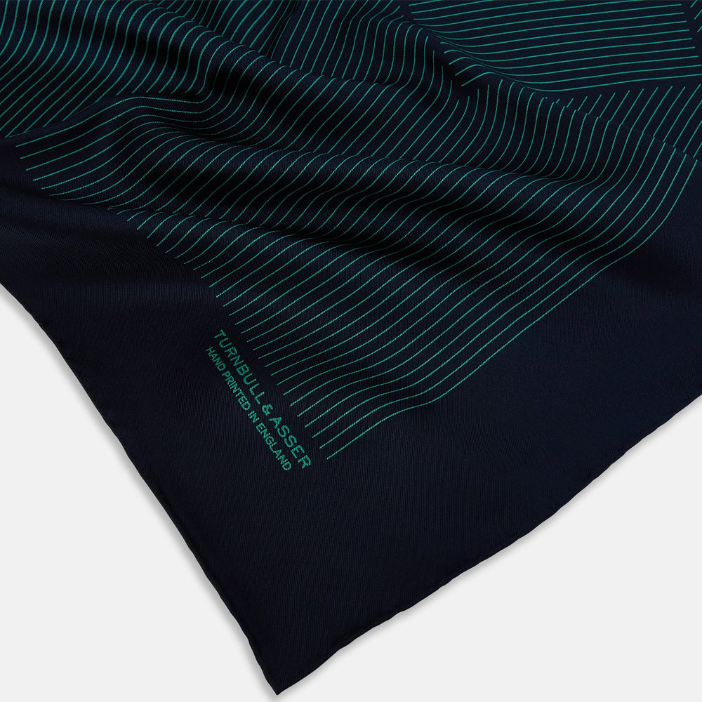 A Navy and Petrol Green Stripe Silk Pocket Square by Turnbull & Asser, featuring thin petrol green stripes and "Turnbull & Asser Hand Printed in England" in the bottom right corner. One corner is folded to display hand-rolled edges.