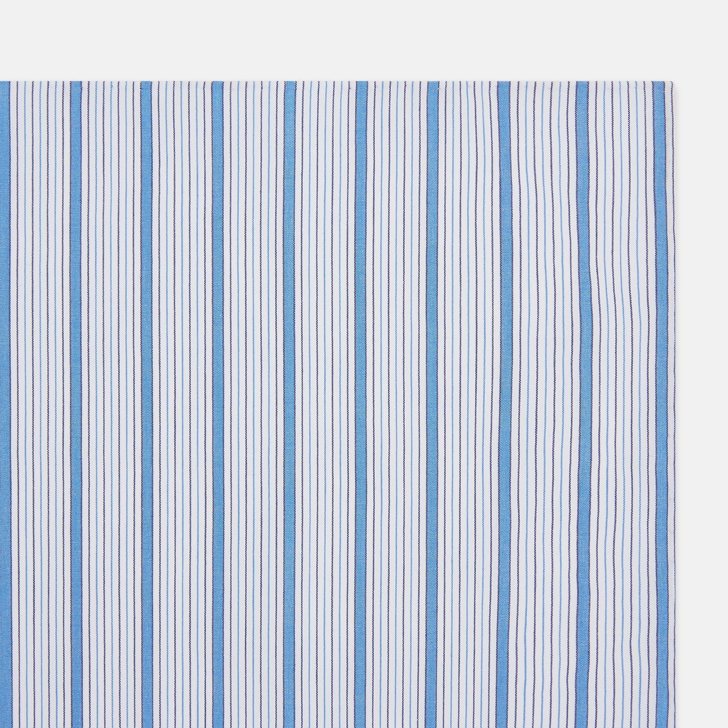 View 2 of product The Hand Rolled Blue Multi Track Stripe Handkerchief by Turnbull & Asser features a square white design with vertical light blue and navy stripes of varying widths—a timeless gentleman’s accessory.